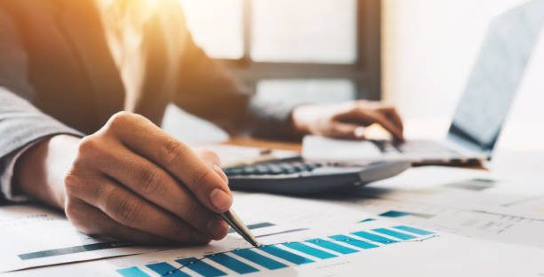 Photo of hands holding pencil and pressing laptop computer for calculating financial marketing