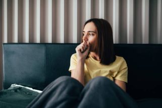 Young woman sick feel unwell sitting in bed at home.