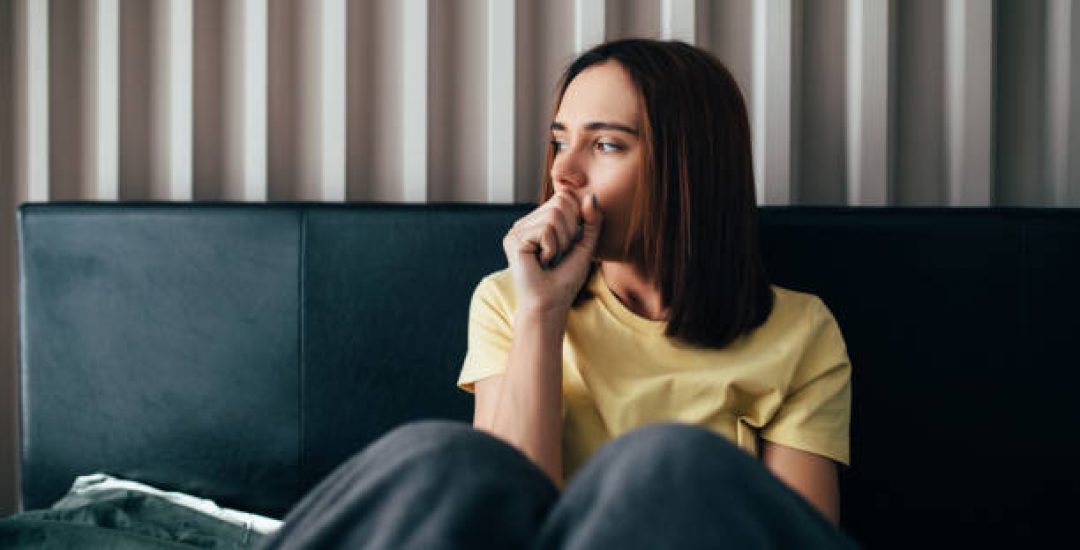 Young woman sick feel unwell sitting in bed at home.