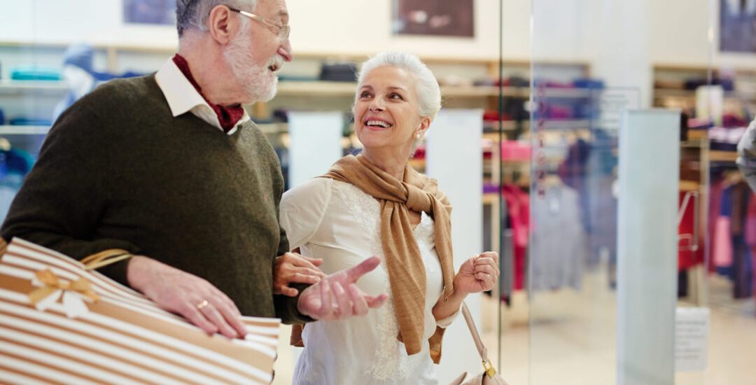 Senior spouses with paperbags talking while shopping in the mall