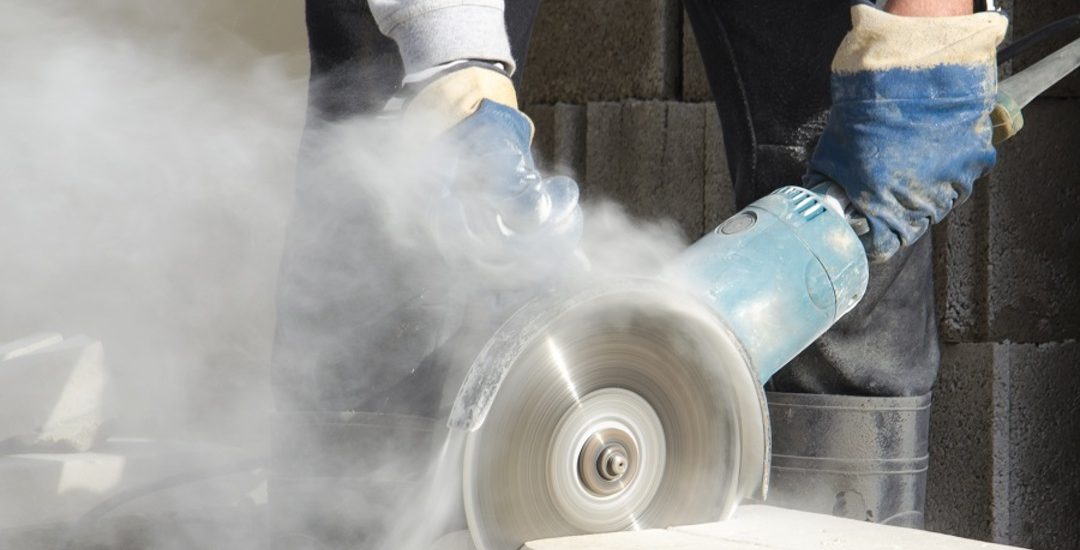 Worker cutting stone with grinder.