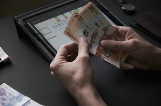 Male hands count colombian pesos banknotes in a dark office