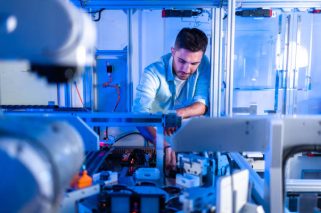 Technological Prosthetic Robot Arm is Tested by Two Professional Development Engineers in a High Tech Research Laboratory with Modern Futuristic Equipment. Man and Female Compare Data on a Personal Computer.