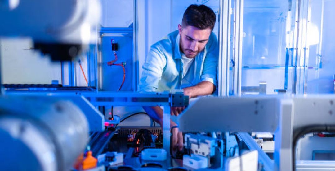 Technological Prosthetic Robot Arm is Tested by Two Professional Development Engineers in a High Tech Research Laboratory with Modern Futuristic Equipment. Man and Female Compare Data on a Personal Computer.