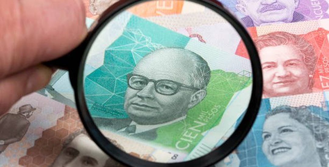 Colombian peso in a magnifying glass a business background