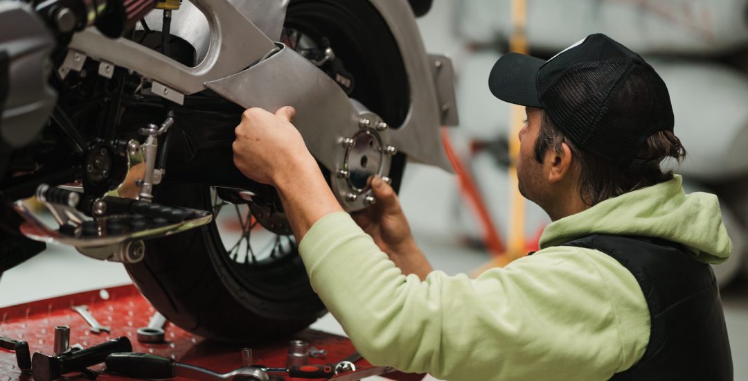 Repairman repair motorcycle, maintenance in garage. Mechanic fixing bike in a modern shop