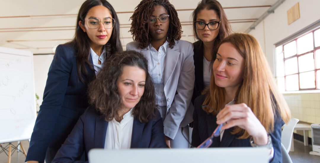 Group of businesswomen working with laptop. Concentrated multiethnic female colleagues using laptop computer and working with new project in office. Women in business concept