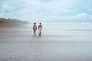 Playa Esterillos - Mamá e hija caminando de espaldas y hablando a un lado costado de la playa en plano general amplio (1)