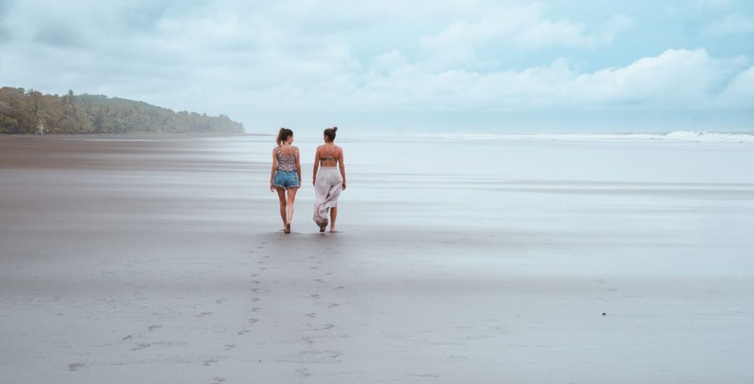 Playa Esterillos - Mamá e hija caminando de espaldas y hablando a un lado costado de la playa en plano general amplio (1)