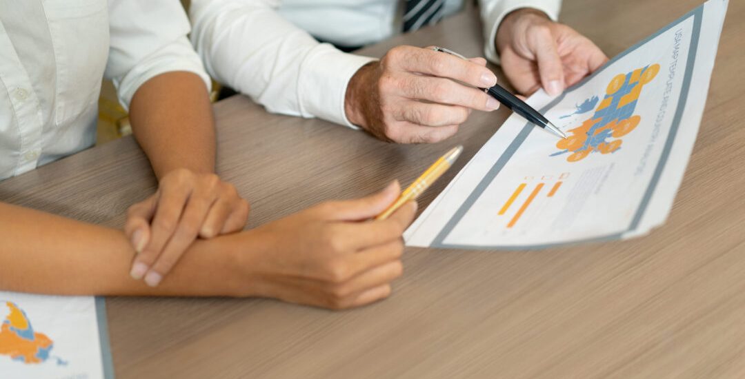 Close-up of multiethnic managers discussing international sales while analyzing data. Unrecognizable analysts viewing map while working with statistics. Forecasting concept