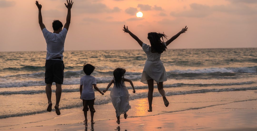 Asian young happy family enjoy vacation on beach in evening. Dad, mom and kid relax running together near sea while silhouette sunset. Lifestyle travel holiday vacation summer concept.