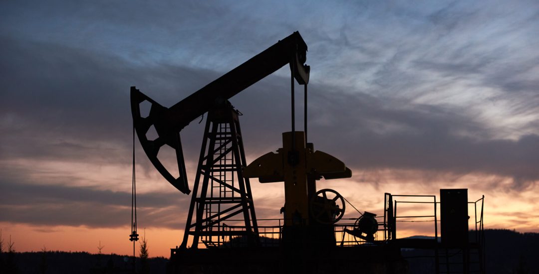 View of evening dramatic sky over long stroke balanced beam petroleum pump jack. Oil field with oil pumping unit or oil pump rocker-machine during sunset. Concept of petroleum industry, oil extraction