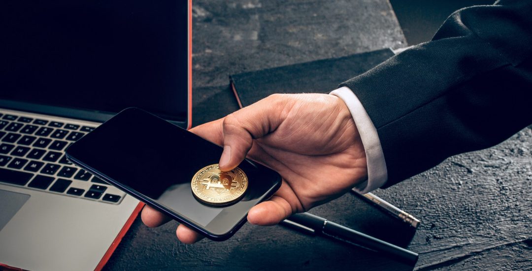 The golden bitcoin and mobile phone in male hands. Cryptocurrency bitcoin coins. Litecoin, Bitcoin, Ethereum, e-commerce, busibess, finance concept. crypto currency symbol. virtual electronic money concepts