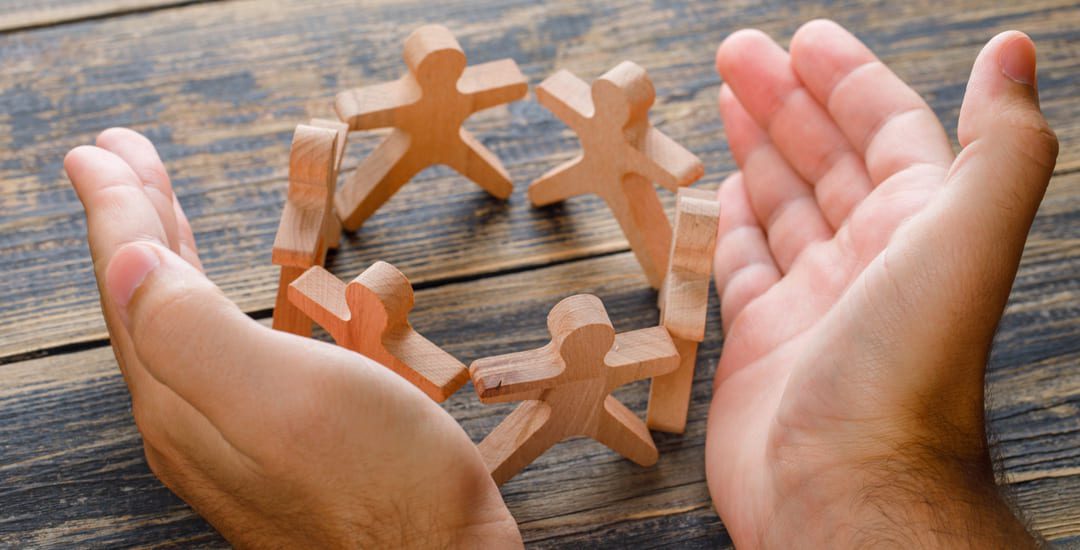 business-success-concept-on-wooden-table-top-view-hands-protecting-wooden-figures-of-people