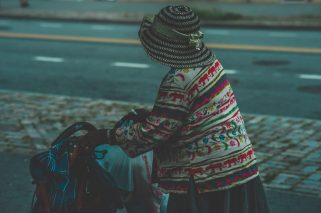 A closeup shot of an old female wearing a hat holding a stroller carriage