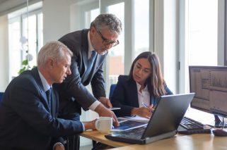 Concentrated colleagues watching statistic charts and talking about work. Professional senior managers and young assistant preparing business plan. Teamwork, management and partnership concept