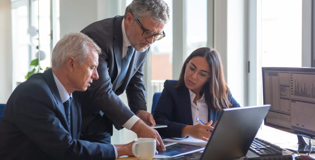 Concentrated colleagues watching statistic charts and talking about work. Professional senior managers and young assistant preparing business plan. Teamwork, management and partnership concept