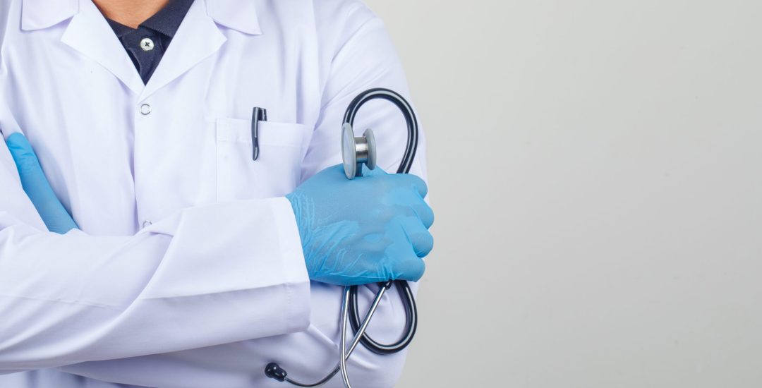 Doctor crossing arms while holding stethoscope in white coat front view.