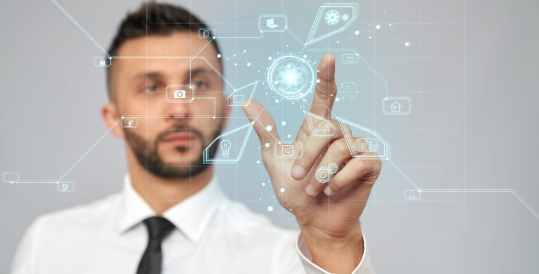 Front view of young serious businessman in formal suit in office. Selective focus of digital tactile charts screen, bearded man clicking virtual icon. Concept of high technologies, digitalization.