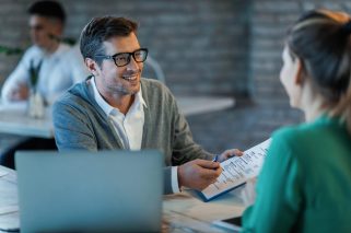 Happy businessman talking to his colleague while going through financial reports in the office.