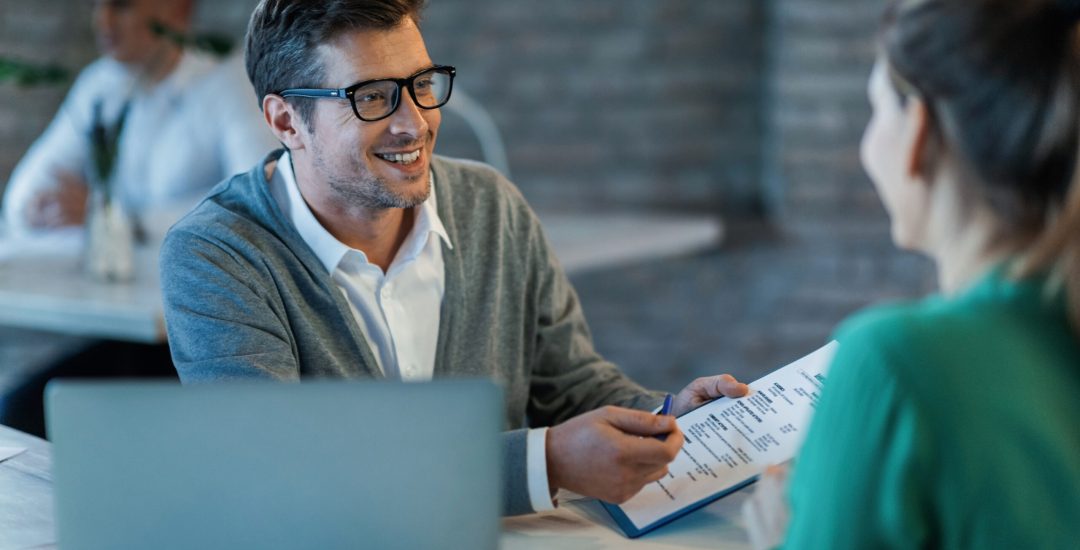 Happy businessman talking to his colleague while going through financial reports in the office.