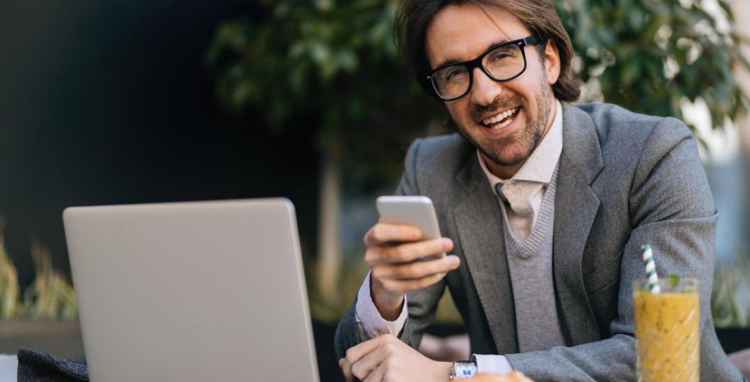 happy-entrepreneur-texting-on-mobile-phone-while-sitting-on-break-in-outdoor-cafe