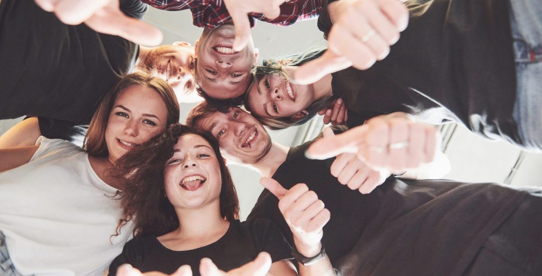 Happy group of friends with their hands together in the middle.