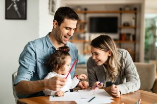 Young happy family drawing on the paper and having fun at home.