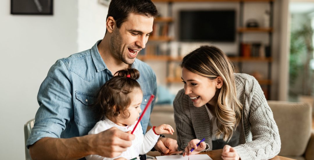 Young happy family drawing on the paper and having fun at home.