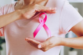 Asian woman show pink ribbon as sign of October Breast Cancer Awareness month