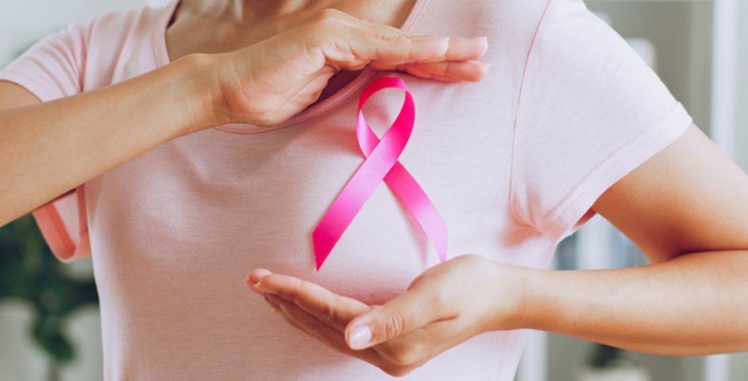 Asian woman show pink ribbon as sign of October Breast Cancer Awareness month