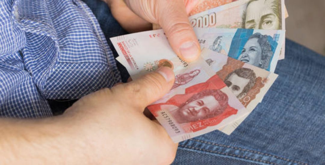 a man holding a bundle of money in his hands, various Colombian pesos