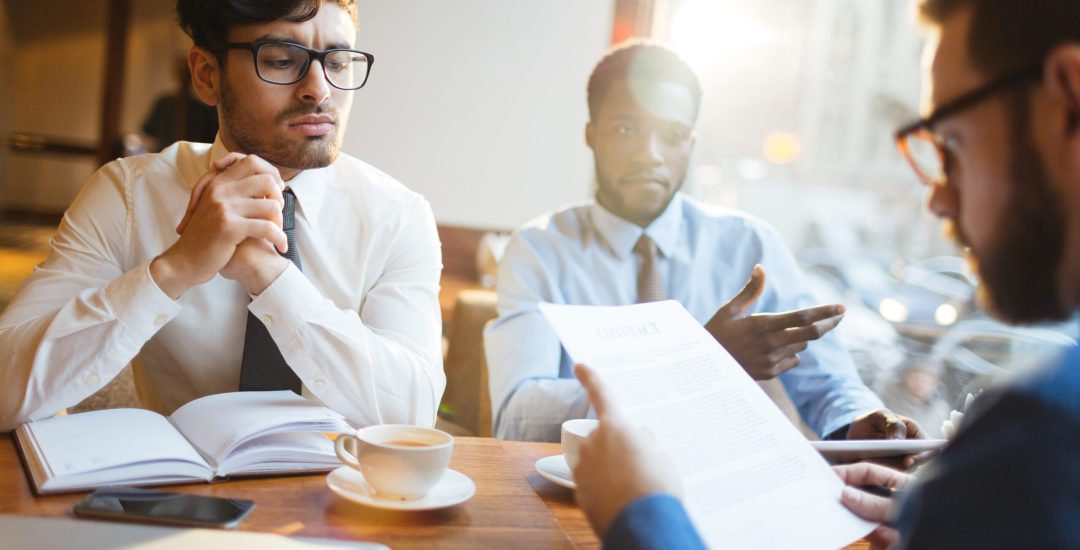 Tense leader looking at potential partner reading contract after negotiation