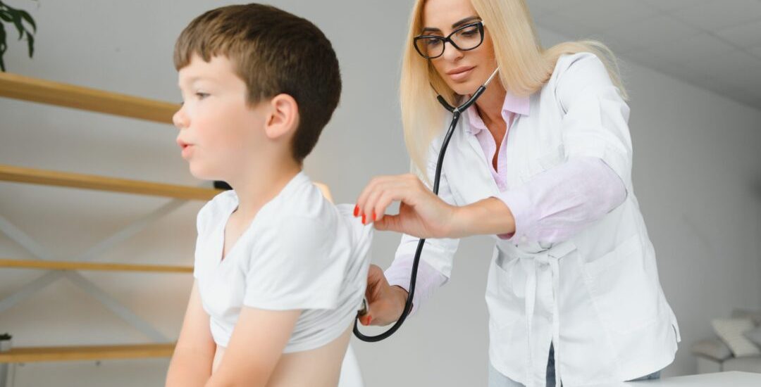Pediatrician listening to breathing in the lungs and heartbeat with stethoscope. Portrait of adorable little boy visiting doctor