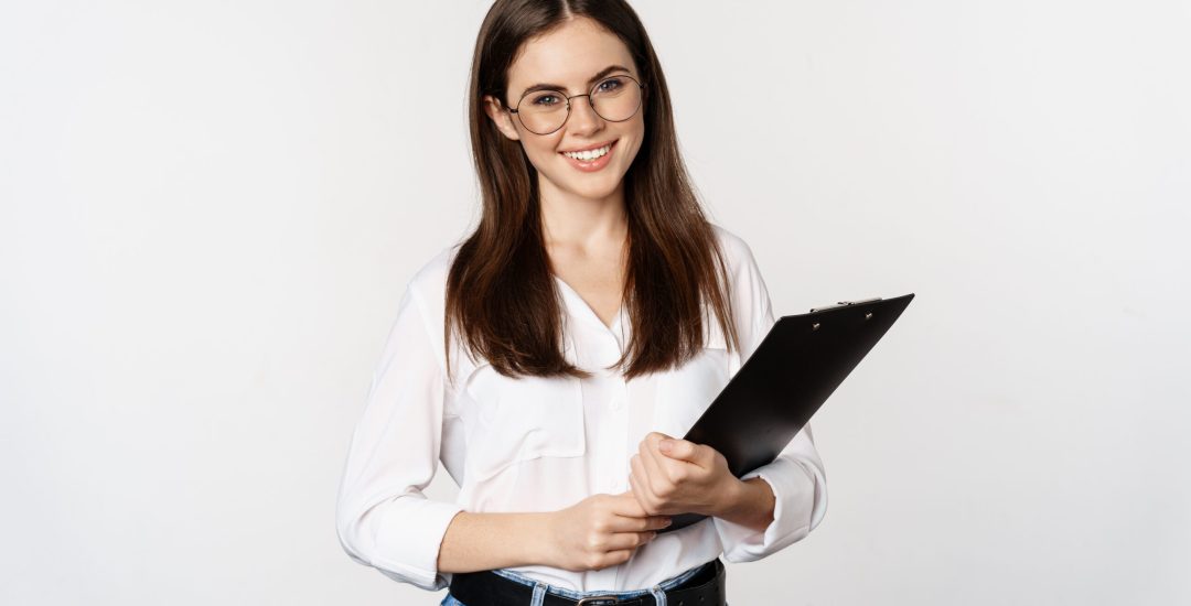 Portrait of corporate woman holding clipboard at work, standing in formal outfit over white background.
