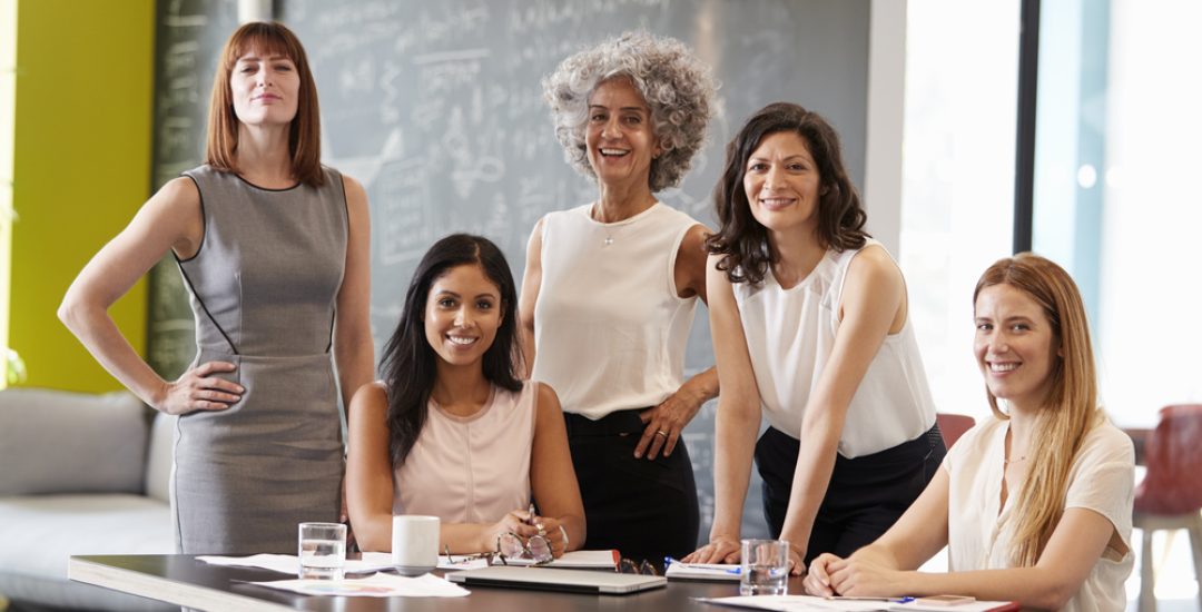Five,Female,Colleagues,At,A,Work,Meeting,Smiling,To,Camera