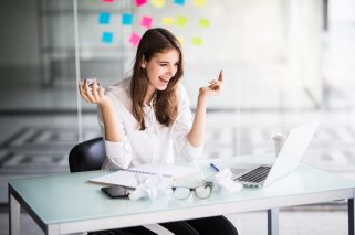 successful businesswoman working on laptop computer in her office dressed up in white strict clothes