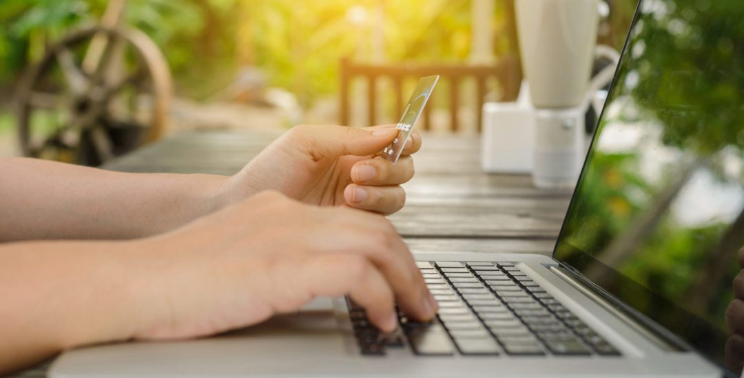 Woman holding credit card in hand and entering security code using laptop, online shopping concept. Panoramic banner.