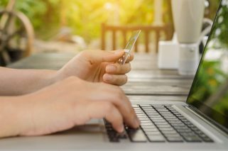 Woman holding credit card in hand and entering security code using laptop, online shopping concept. Panoramic banner.