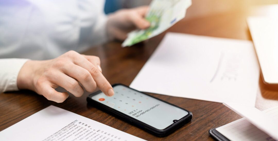 Woman working with finances on the table. Smartphone, money, notepad