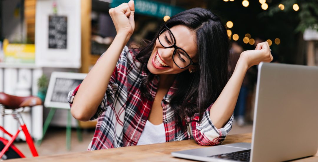 Wonderful female student sitting in cafe with laptop and laughing. Pleasant freelancer in glasses expressing happiness.
