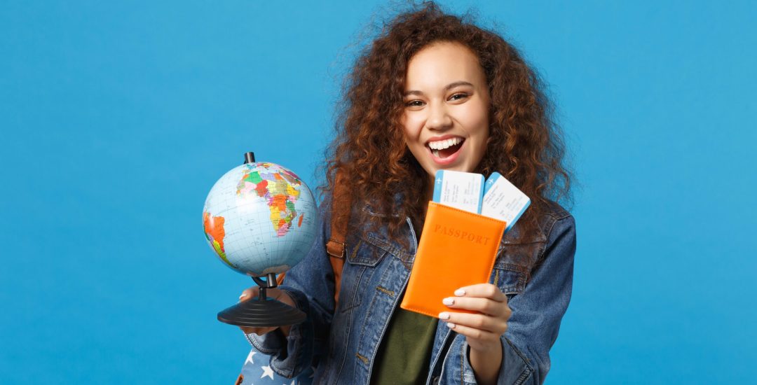 Young african american girl teen student in denim clothes, backpack hold pass isolated on blue wall background studio portrait. Education in high school university college concept. Mock up copy space