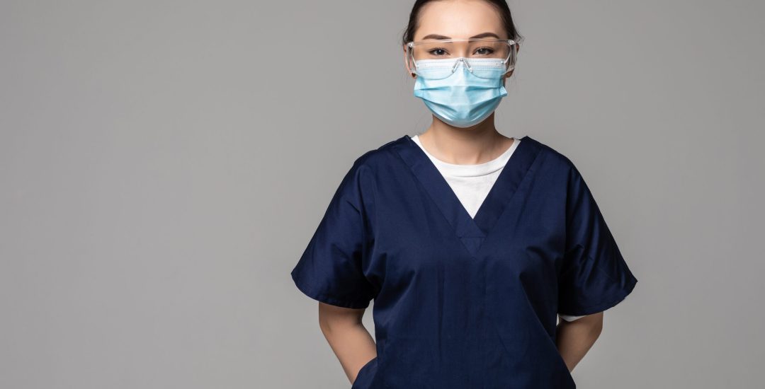 Asian Chinese medicine doctor woman or hospital nurse in scrubs using protective medical face mask in prevention against virus infection