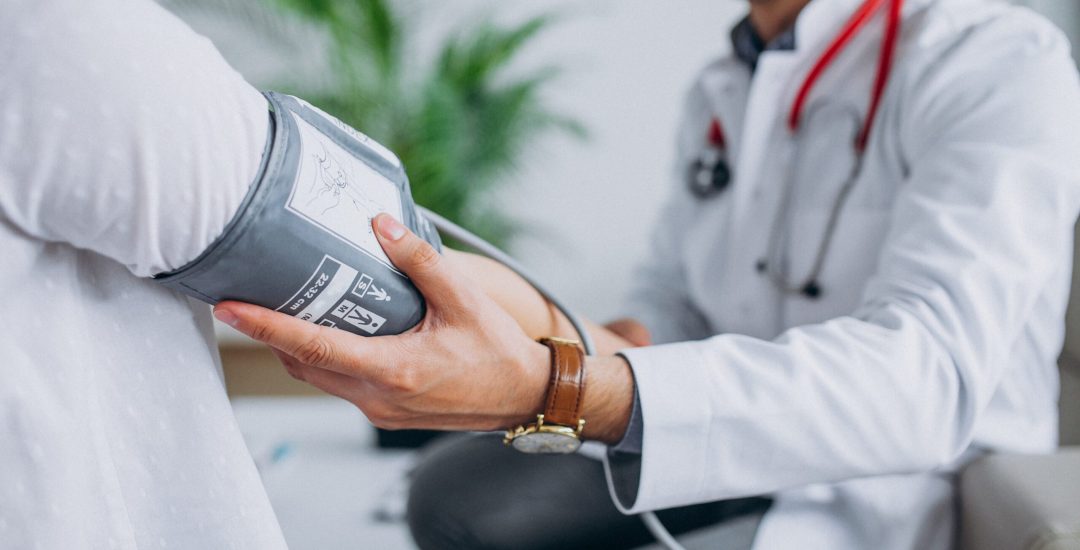 Young male psysician with patient measuring blood pressure